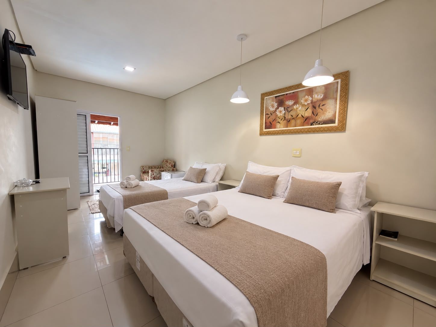 A hotel room with two beds, a TV, a painting, and a view of the outside.