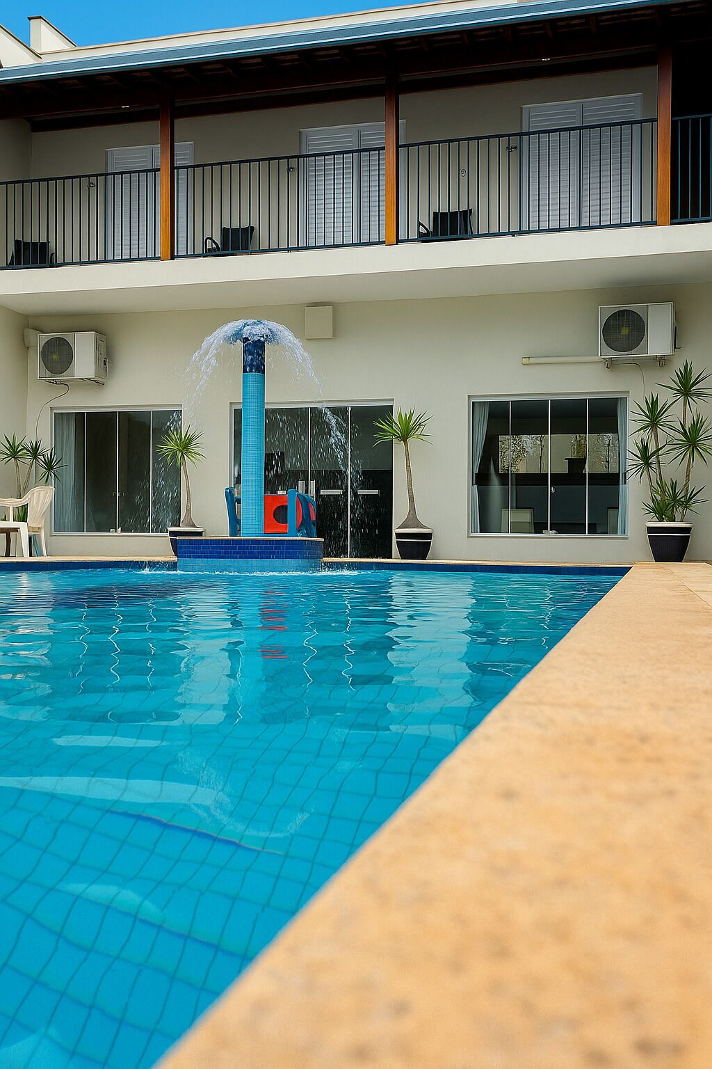 A swimming pool with a water fountain, potted plants, and a covered outdoor seating area.