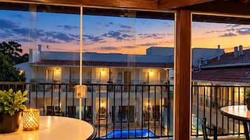 Una terraza con piscina, suelo de piedra y vista a un edificio con balcones.