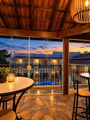 A terrace with a pool, stone flooring, and a view of a building with balconies. - Hotel Picadão Eventos (São Pedro)