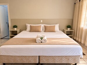 A hotel room with a large bed, two bedside tables, and a window with curtains. - Hotel Picadão Eventos (São Pedro)