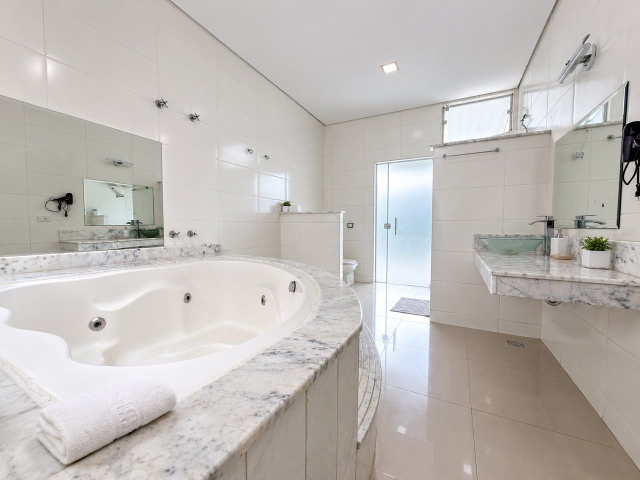 Une salle de bain moderne avec une grande baignoire, une douche à l’italienne en verre et un comptoir en marbre.