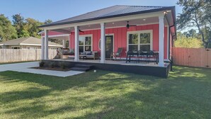 Ein zweigeschossiges Haus mit überdachter Terrasse und umzäunter Garten.