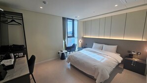 A modern hotel room with a large bed, a desk with a chair, a wardrobe, and a small table. - The Gleam Hotel (Incheon)