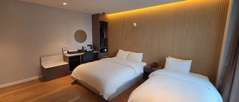 A modern hotel room with two beds, a desk, and a vanity.