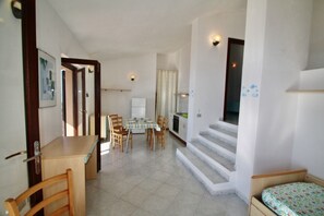 A compact living space with a dining area, kitchen, and a small bedroom. - Three-room villa with sea view of approximately 55 m2 furnished in a simple and essential way consisting of a living room with double sofa bed, kitchenette equipped with gas stove.A double bedroom with wardrobe and another bedroom with two single beds, b (Trinita' d'Agultu e Vignola)