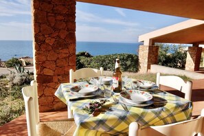 An outdoor dining area with a table set for two, overlooking the sea.