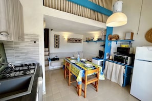 A compact kitchen with a gas stove, a dining table with chairs, and a microwave.