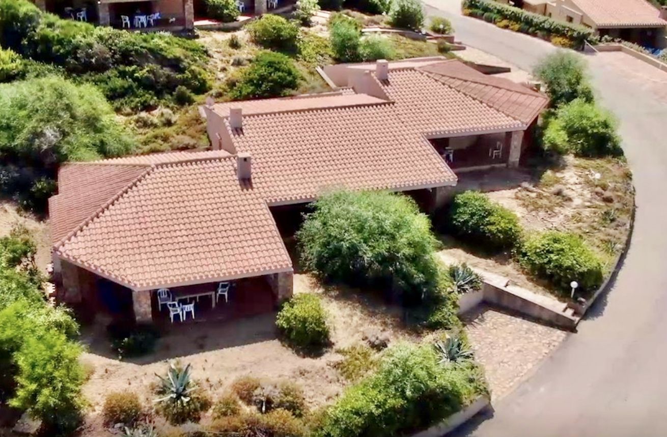 A residential area with two houses featuring tiled roofs and surrounded by greenery.