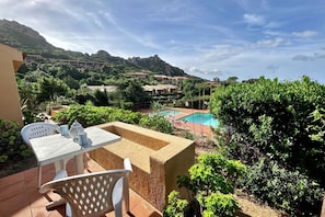 A patio with a table and chairs, a pool, and a mountainous backdrop. - On the stretch of coast between Santa Teresa di Gallura and Isola Rossa, in the north of Sardinia, lies the Costa Paradiso residential complex. The resort of Costa Paradiso is an oasis of tranquillity overlooking an <b>unspoilt natural landscape</b> and  (Trinita' d'Agultu e Vignola)