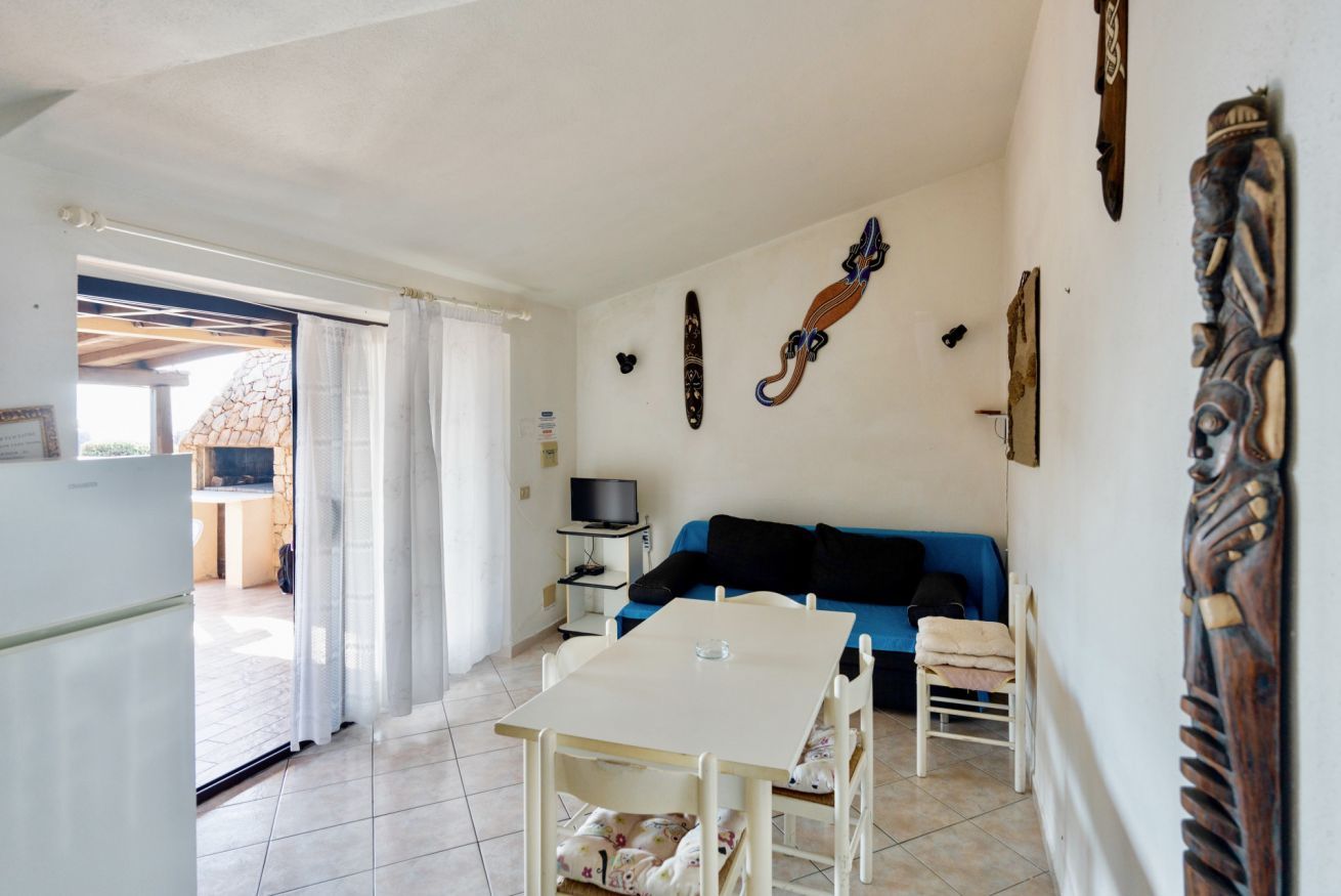 A compact living space with a dining table, a blue sofa, and a TV.