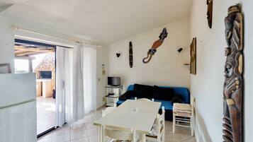A compact living space with a dining table, a blue sofa, and a TV.