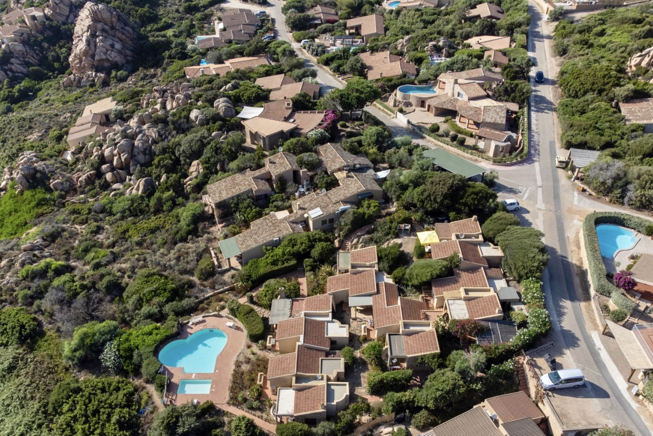 An aerial view of a residential area with houses, a swimming pool, and a road.