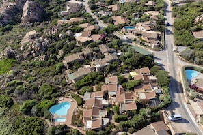 An aerial view of a residential area with houses, a swimming pool, and a road.