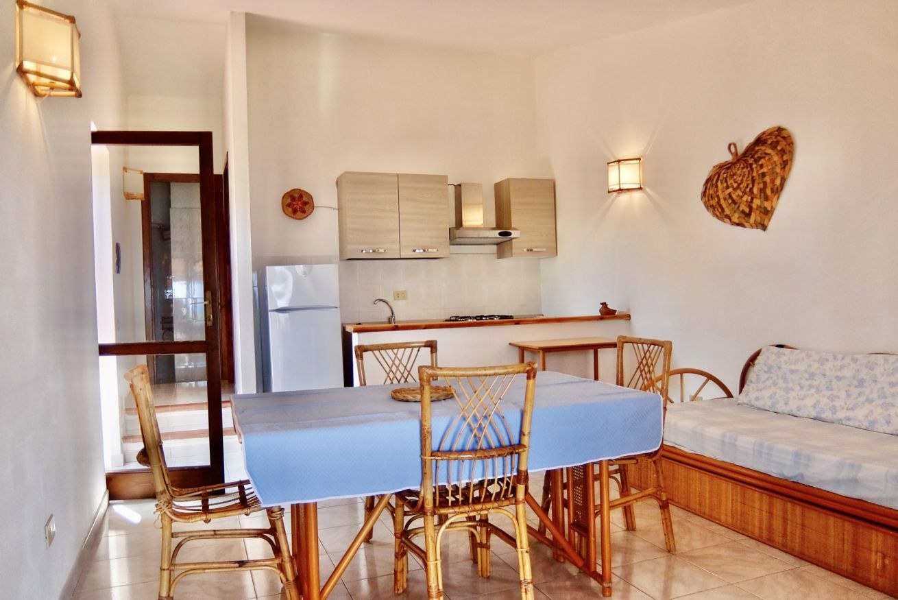Una cocina compacta con armarios de madera y un comedor con mesa y sillas.