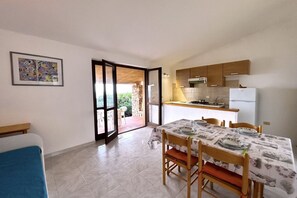 A dining area with a table set for four, a kitchen with wooden cabinets, and a door leading to an outdoor patio.