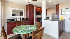 A modern kitchen with dark wood cabinets, a central island, and a ceiling fan. - 🌴Beautiful condo located at higher elevations, Expansive Ocean Views🌴 (Holualoa)