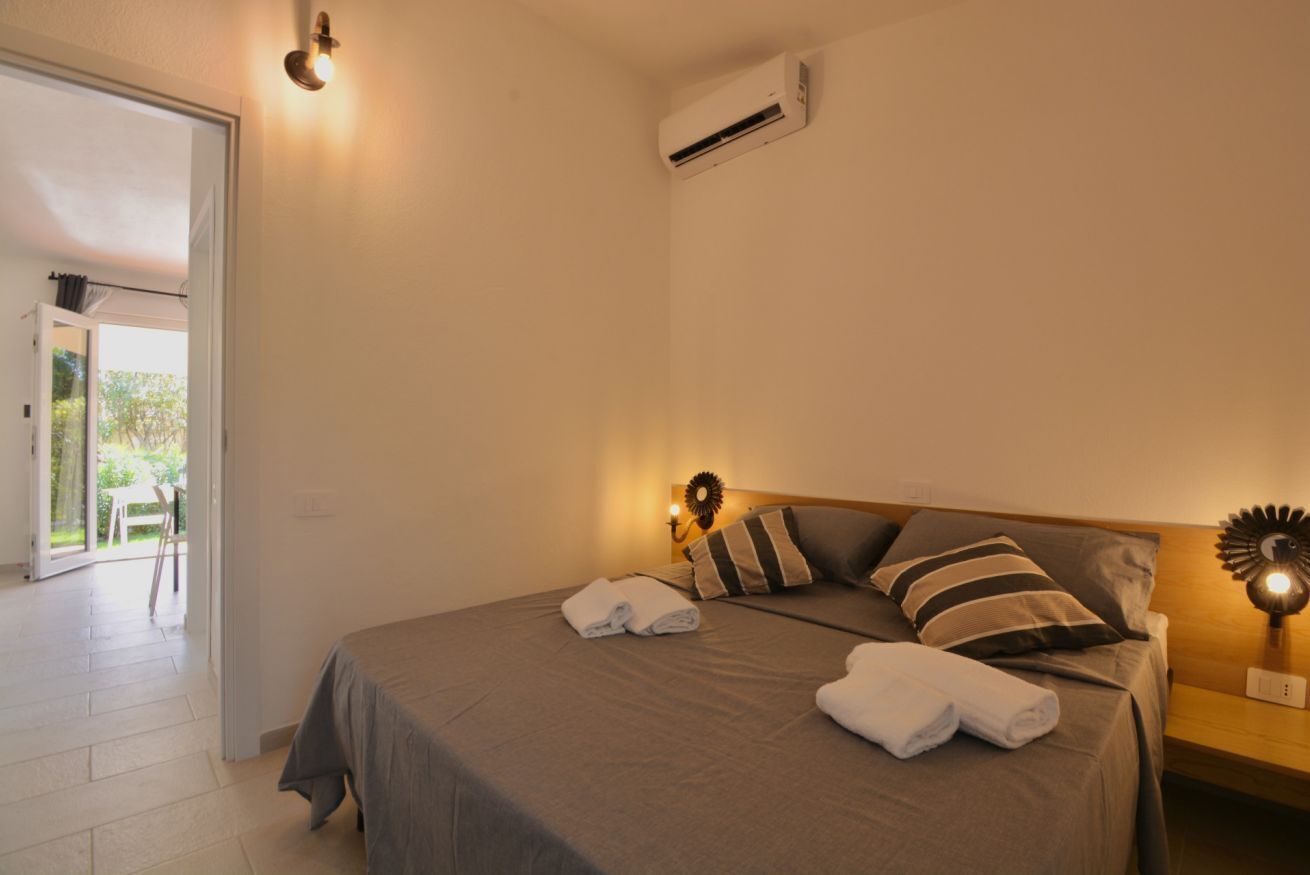 A bedroom with a bed, pillows, a nightstand, and a wall-mounted air conditioner.