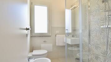 Un bagno con il water, lavandino e doccia.