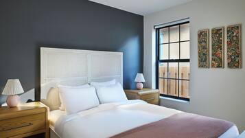 A bedroom with a bed, two bedside tables, a window, and wall art.