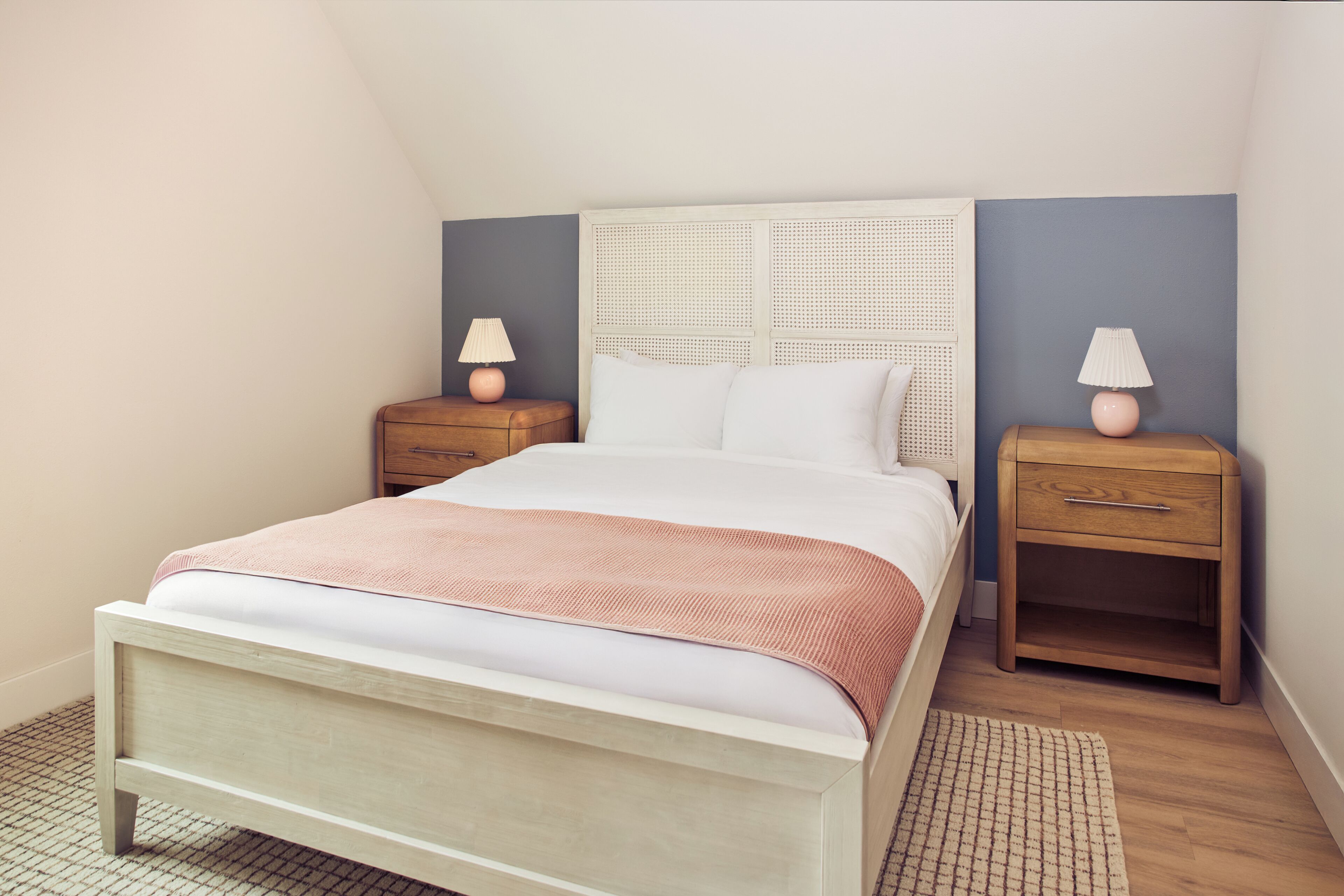 A bedroom with a bed, two bedside tables, a headboard, and a floor lamp.
