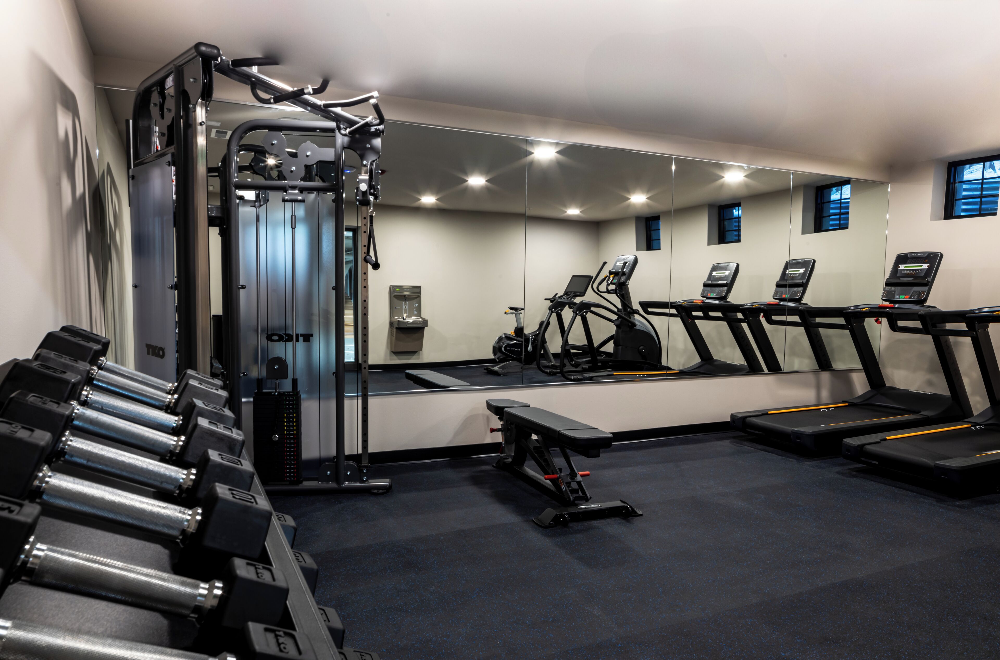Un gimnasio con máquinas de pesas, cintas de correr y mancuernas.