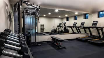 Un gimnasio con máquinas de pesas, cintas de correr y mancuernas.