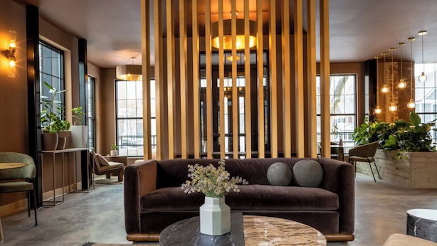 Un intérieur moderne avec un canapé marron, une table basse ronde en marbre et un vase décoratif orné de fleurs.