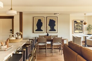 Un comedor con mesa y sillas de madera, un sofá y cuadros en la pared.