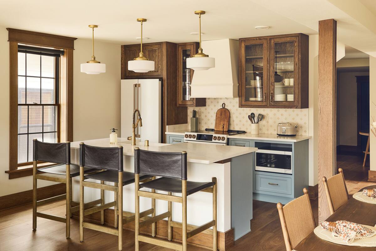 A kitchen with wooden cabinets, a central island, bar stools, and pendant lighting.