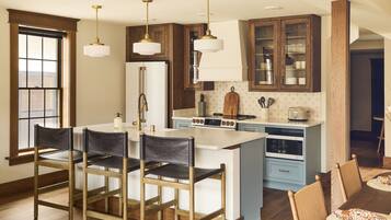 A kitchen with wooden cabinets, a central island, bar stools, and pendant lighting.