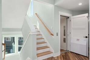 A modern interior with a staircase, a door, and a view through a window.