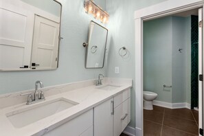 A bathroom with a white vanity, a mirror, a sink, and a toilet.