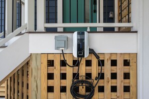 An outdoor electrical outlet mounted on a wooden fence with a cable connected to it.