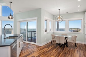 A modern kitchen with a large island, a dining area with a round table and chairs, and large windows offering a view of the city.