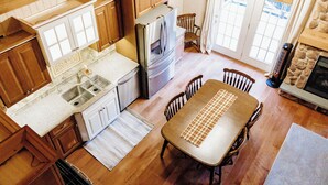 Una cocina con armarios de madera, un refrigerador, un fregadero y una mesa de comedor con sillas.