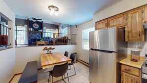 Une cuisine de taille réduite avec une table à manger en bois, un réfrigérateur en acier inoxydable et des placards en bois.
