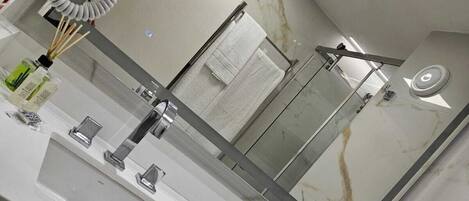 A modern bathroom with a large mirror, a sink, a toilet, and a hairdryer.