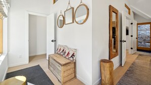 A hallway with a wooden bench, a mirror, and a door.