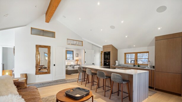 A spacious living area with a large sofa, a coffee table, and a kitchen with a bar area.
