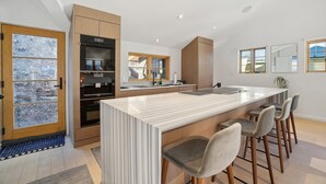 A modern kitchen with a central island, wooden cabinets, and a large window.