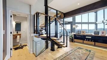 Un intérieur moderne avec un escalier en colimaçon, une grande fenêtre offrant une vue dégagée et un plancher en bois.