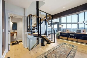 Een modern interieur met een spiltrap, een groot raam met uitzicht en een houten vloer.