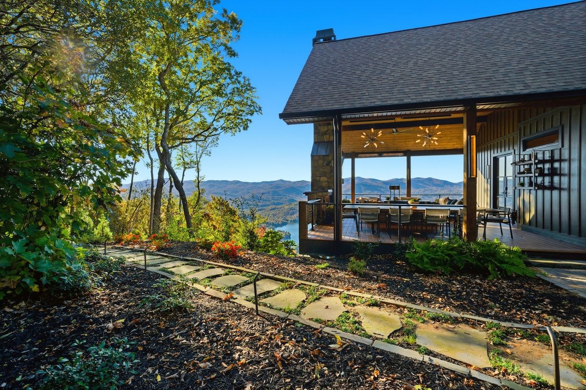 A modern house with a covered patio, stone pathway, and a view of mountains.