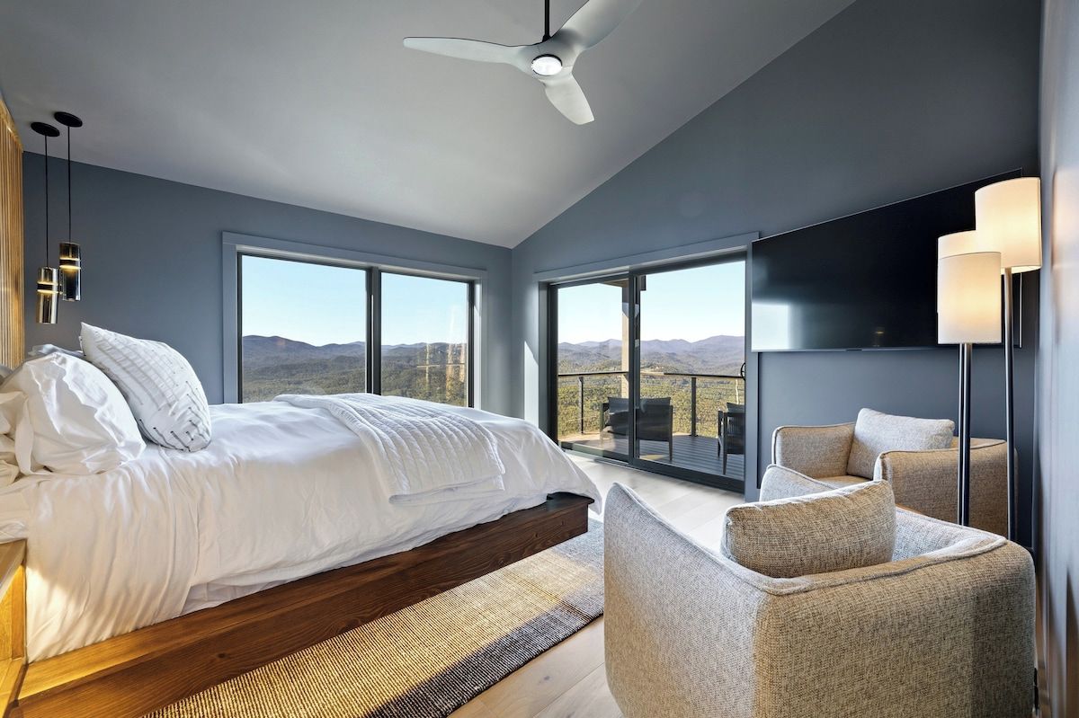Une chambre moderne avec un lit, un coin salon et une grande fenêtre donnant sur les montagnes.