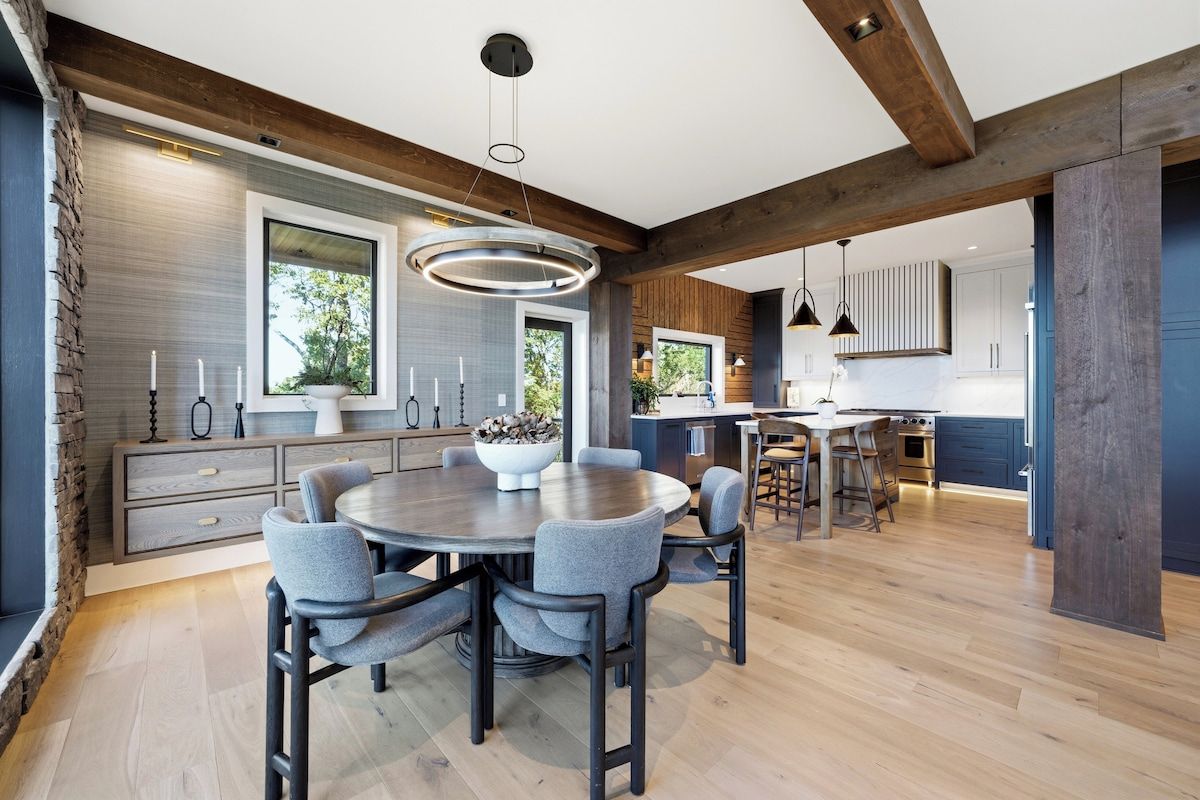 Une cuisine moderne avec une table à manger ronde, des meubles de rangement intégrés et une grande fenêtre.