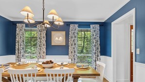 Une salle à manger avec une table en bois, des chaises blanches et un lustre.