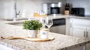 Un comptoir de cuisine orné d’une plante en pot, de deux verres à vin et d’une tasse blanche portant un logo.