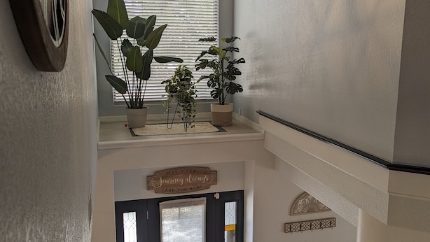 A multi-level interior with a geometric pendant light, potted plants, a decorative sign, and a staircase. - Charming Cocoa Village Oasis (Cocoa)