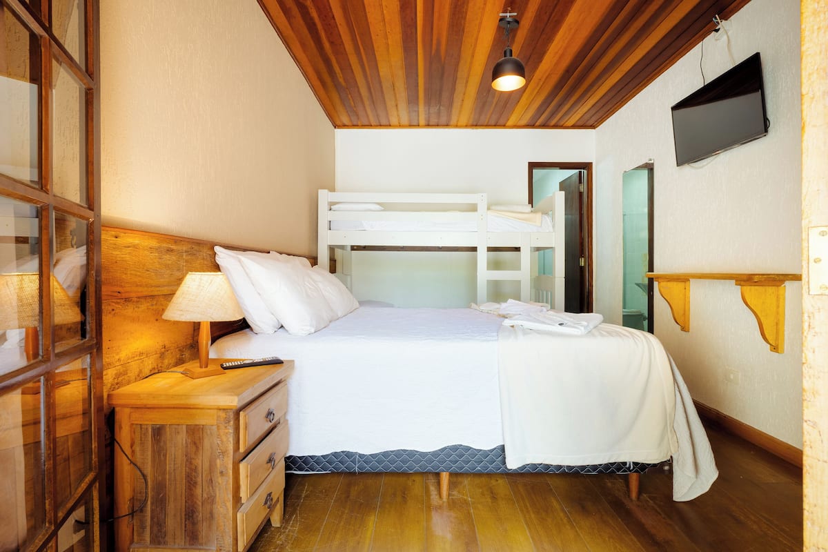 Un dormitorio con literas, muebles de madera, una lámpara de noche y un televisor en la pared.